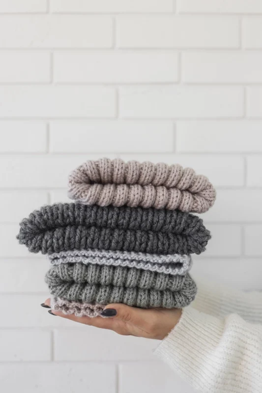 A woman holding neatly folded wool knitwear, showing proper merino wool care and storage to maintain softness and shape.